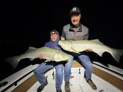Two anglers with striped bass caught in Maine