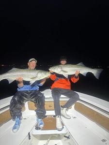 Two striped bass being held by two people in Wells