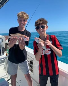 Two anglers displaying freshly caught fish on fishing boat in Florida waters