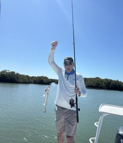 Angler celebrating successful catch with fish and fishing rod on boat in Naples Florida waters