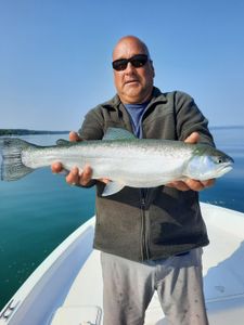 Photograph of a fisherman holding a large Rainbow Trout in Kaleva