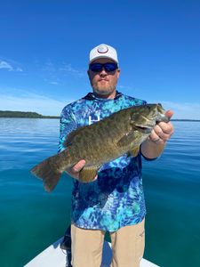 A fisherman holding a large smallmouth bass caught in Kaleva
