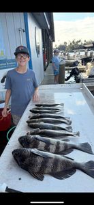 Two anglers fishing on the coast of Florida, catching three black drum fish.