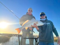 Two anglers holding a large redfish on a boat in Welches OR
