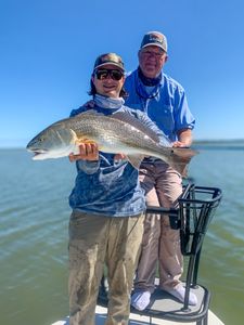 Two anglers on fishing boat displaying caught redfish in Welches OR waters
