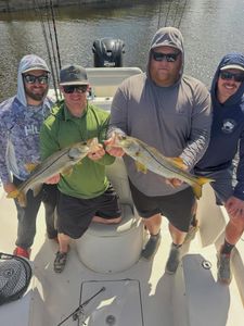Four anglers on fishing boat displaying two caught snook in Fort Myers FL
