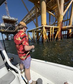 Fishing boat near offshore oil rig platform in Gulf waters off Dauphin Island Alabama