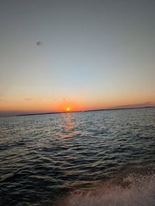 Sunset over water at Port Clinton OH fishing location with birds flying in orange sky