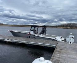 White fishing boat docked at wooden pier in Newburyport MA with outboard motor and fishing rod holders