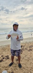 Florida pompano catch displayed on New Smyrna Beach with fishing rods in background