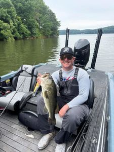 Bass fishing catch on lake in Fort Worth TX with fishing boat and wooded shoreline