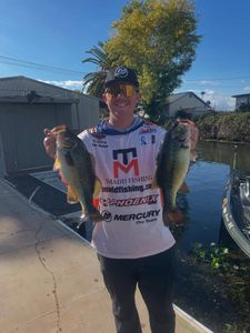 Angler displaying two freshwater bass caught while fishing in Fort Worth TX