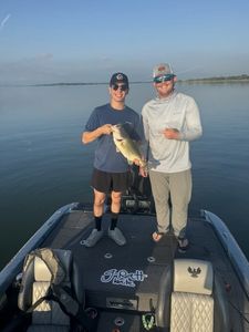 Two anglers on fishing boat holding freshly caught bass in Fort Worth TX waters