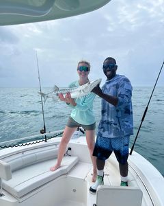 Two people fishing in the waters of Key Largo, catching a great barracuda.