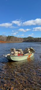 Fishing boat with comfortable seating anchored in shallow clear water near forested shoreline in South Portland Maine