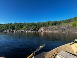 Fishing net and boat view of rocky shoreline with forested hills in South Portland Maine