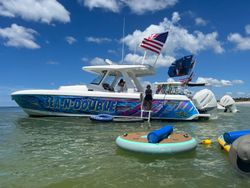 White sport fishing boat named Sea-N-Double anchored in shallow water with inflatable paddleboard floating nearby in St. Petersburg FL