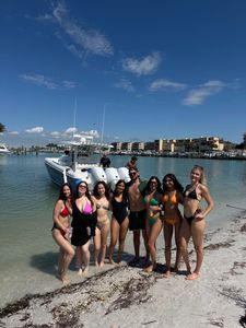 Group posing on beach with charter boat in St. Petersburg FL waters
