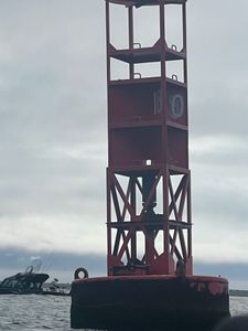 Red navigation buoy with tall tower structure in water near Clackamas OR fishing area
