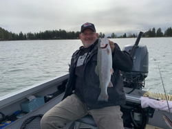 Angler holding large trout on fishing boat in Clackamas Oregon