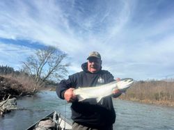 Angler holding large salmon on river in Gold Beach Oregon