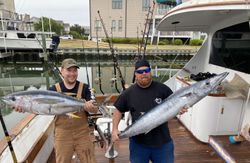 Two anglers holding caught wahoo fish and yellowfin tuna in Morehead City