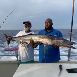 Two anglers displaying large barracuda catch on fishing boat deck in Fort Pierce FL