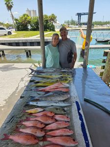 Fishing catch display in Fort Pierce FL showing King Mackerel, Grey Triggerfish, Great Barracuda and other species on cleaning table at marina