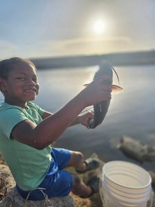 Young angler holding freshly caught fish by the water in Fort Pierce FL