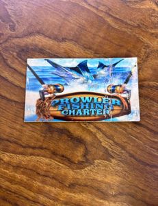 Prowler Fishing Charter business card on wooden surface featuring marlin jumping from ocean water