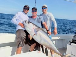 Three anglers posing with large yellowfin tuna catch on fishing boat in Tavernier FL