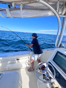 Fishing from boat deck with rod over ocean water in East Dennis MA
