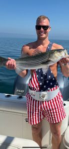 Angler holds striped bass caught while fishing in MA