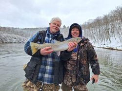 A fisherman holding a large rainbow trout in Cadillac