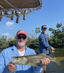 Two anglers holding a large freshwater fish against the backdrop of Florida's stunning scenery.