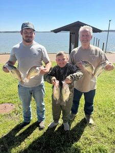 Successful fishing trip in Pope MS showing multiple caught fish displayed on grassy area near lake with dock structure