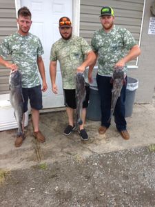 Three anglers holding their catch of the day near the Cross