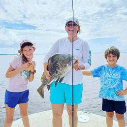 Angler holding a big black drum fish against the backdrop of Santa Rosa Beach