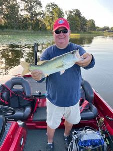 Angler holding large bass fish on fishing boat in Tavares FL lake
