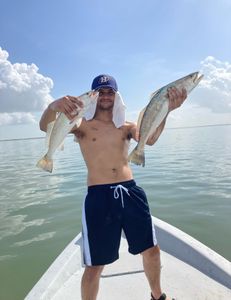 A fisherman holding two large fish in Galveston