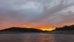 Sunset over desert lake with orange and pink sky reflecting on water surface in Morristown Arizona