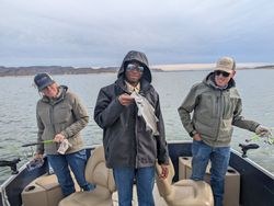 A serene fishing outing on the lake, with three friends enjoying the outdoors and their shared pastime against the backdrop of the rugged mountain landscape.