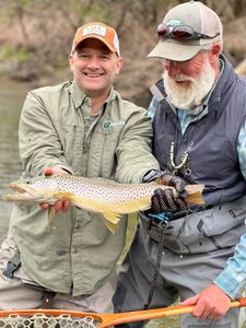 A person fishing in Vermont with a 18-inch fish