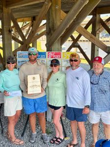 Fishing tournament winners holding awards and certificates under wooden pavilion in Spanish Fort AL