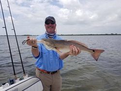 Photograph of a fisherman holding a large redfish in Florida