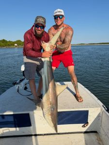 Two anglers holding a caught blacktip shark on a fishing boat in Cedar Point NC waters