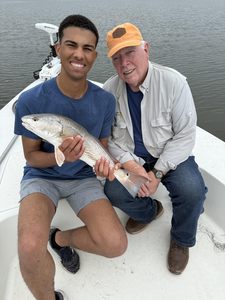 Reeling in a 13-inch redfish on a clear day in Cedar Point!