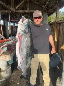 Angler holding a large fish against the backdrop of Gold Beach