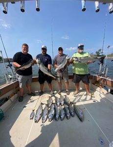 Group shows off fresh salmon haul on sunny day.