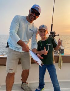 Two people fishing in Muskegon with a small 10-inch fish